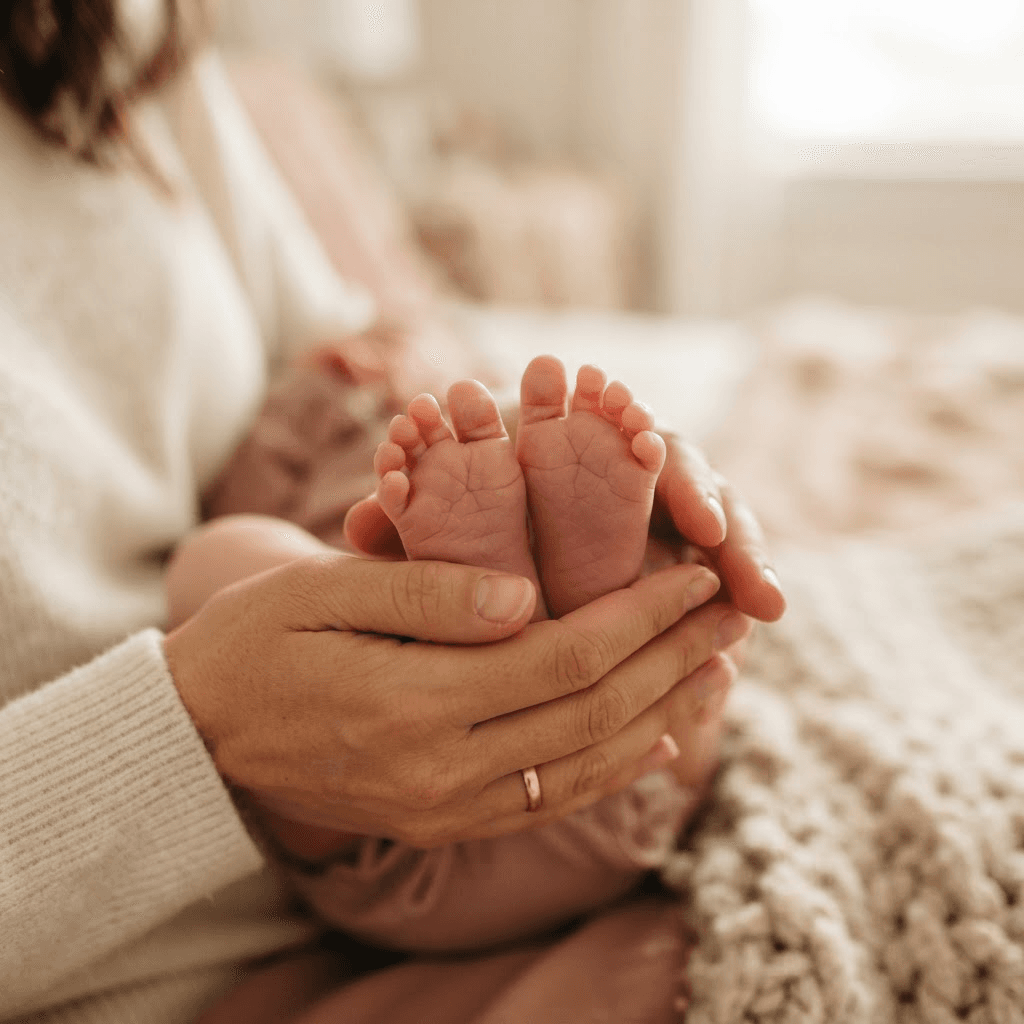 A newborn baby's tiny feet gently cradled in a parent's hands